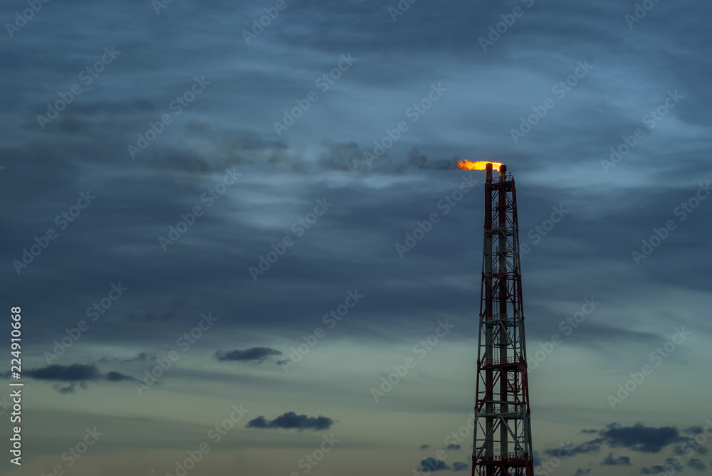 industrial flare for the combustion of associated petroleum gas against the background of sky industrial flare for the combustion of associated petroleum gas against the background of sky