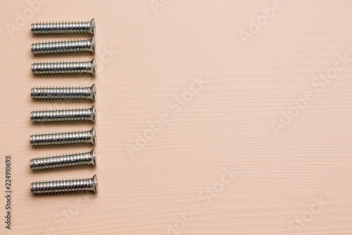 Self-tapping screw on a wooden background. 