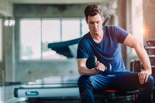 Fit caucasian handsome young man and big muscle in sportswear. Young man holding dumbbell during an exercise class in a gym. Healthy sports lifestyle, Fitness concept. with copy space for your text.