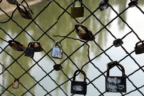 Padlocks as symbol of love on a  wire fence bridge with water background. Locks bridge.
