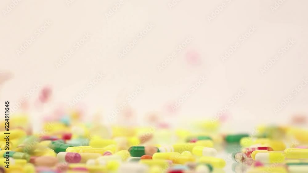 A lot of colorful medication and pills dropping on a grey background A lot of colorful medication and pills dropping on a grey background