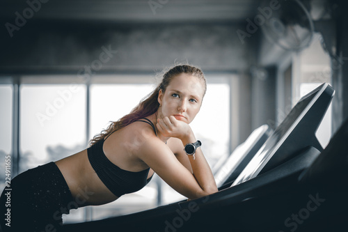 Young woman attractive fitness exercise workout in gym. Woman stretching the muscles and relaxing after exercise on machine treadmill at fitness gym club.