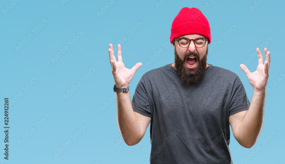 Naklejka premium Young caucasian hipster man wearing glasses over isolated background celebrating mad and crazy for success with arms raised and closed eyes screaming excited. Winner concept
