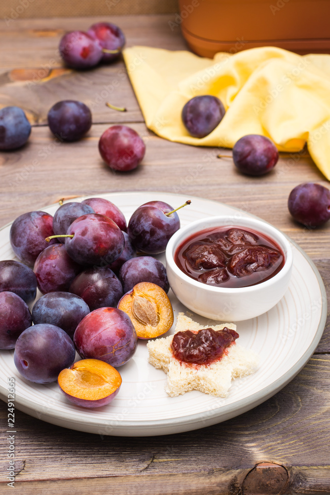 Appetizing bruschetta from fresh bread with plum jam and ripe berries of blue plums on a plate on a wooden table Appetizing bruschetta from fresh bread with plum jam and ripe berries of blue plums on a plate on a wooden table