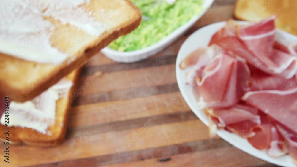 A woman spreads mayonnaise on a slice of toast over a cutting board A woman spreads mayonnaise on a slice of toast over a cutting board