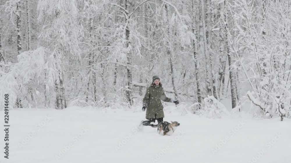 Young Beautiful Caucasian Girl Woman Dressed In Jacket Playing With Puppy Of Mixed Breed Dog In Winter Forest In Snowy Day. Girl And Dog Running Together In Forest Slo-mo Slow Motion Slow-mo Young Beautiful Caucasian Girl Woman Dressed In Jacket Playing With Puppy Of Mixed Breed Dog In Winter Forest In Snowy Day. Girl And Dog Running Together In Forest Slo-mo Slow Motion Slow-mo