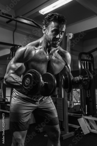 White Muscular man training his biceps in the gym by dumbbells BW © Peterfilm