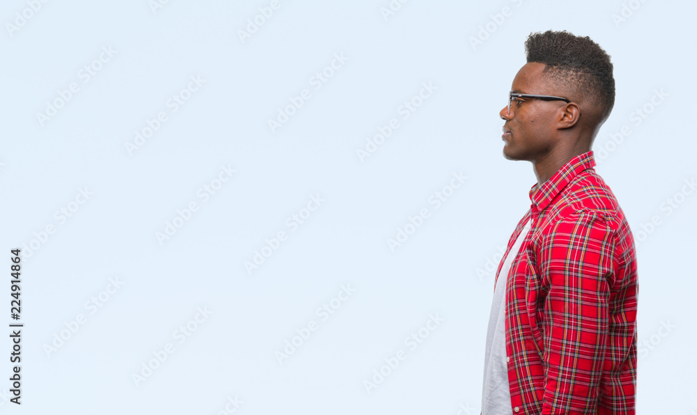 Young african american man over isolated background looking to side, relax profile pose with natural face with confident smile. Young african american man over isolated background looking to side, relax profile pose with natural face with confident smile.