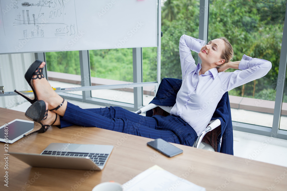 business woman relaxing or sleeping with her feet on the desk in office.  female boss worker close eyes sitting with legs on the table in the resting  time at work place Stock