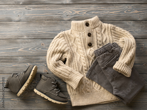Fashion children's clothing, shoes (knit sweater, jeans, suede boots). Outfit for little boy. Winter, autumn collection. Organic cotton. Top view, flat lay