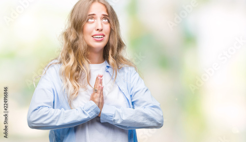 Beautiful young blonde woman over isolated background begging and praying with hands together with hope expression on face very emotional and worried. Asking for forgiveness. Religion concept. © Krakenimages.com