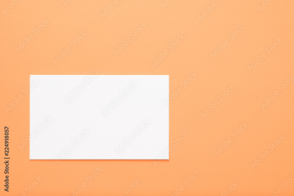 blank white paper on orange background. copy space for message or text. communication and advertisement concept. blank white paper on orange background. copy space for message or text. communication and advertisement concept.