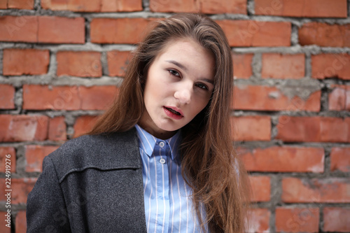 Young beautiful girl near red brick wall posing