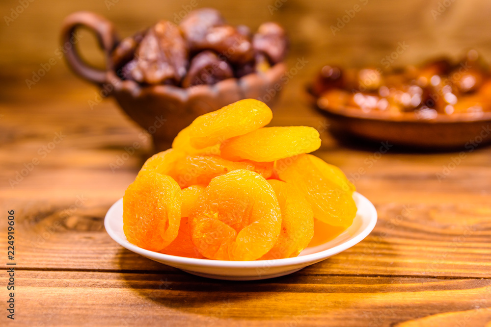 Dried apricots and date fruits on wooden table Dried apricots and date fruits on wooden table