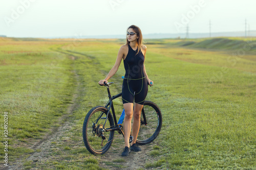 Girl on a mountain bike on offroad, beautiful portrait of a cyclist at sunset 