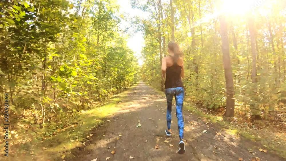 Young, fit woman is running on the path in the park. Young, fit woman is running on the path in the park.