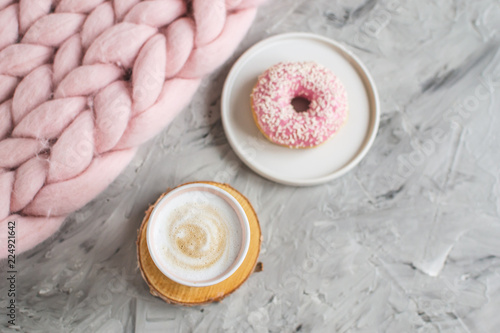 Cup with cappuccino, doughnut, pink pastel giant blanket, flowers, bedroom, morning concept