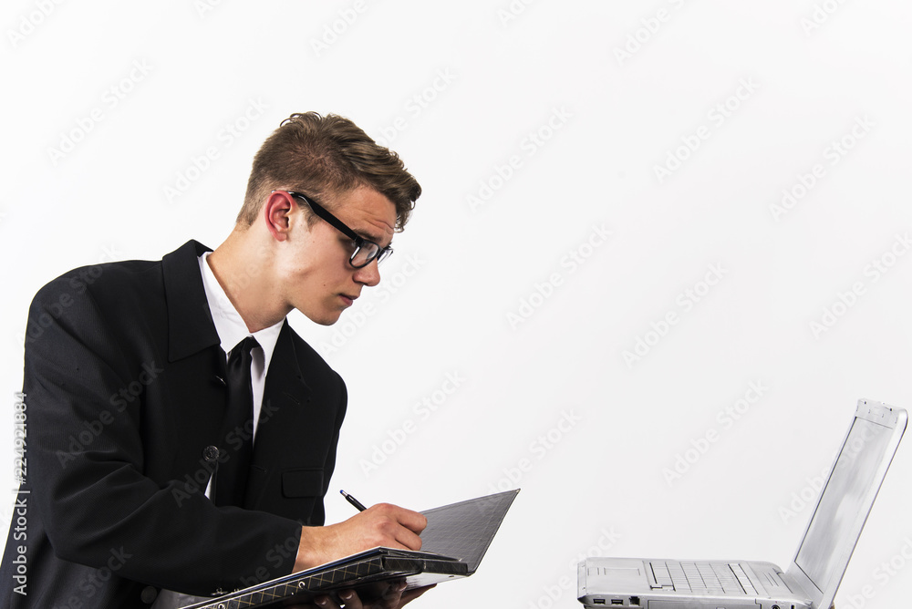 young man in classic black suit with laptop and papers office and business concept young man in classic black suit with laptop and papers office and business concept