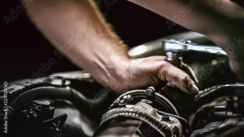 Auto mechanic working on car engine in mechanics garage. Repair service. authentic close-up shot