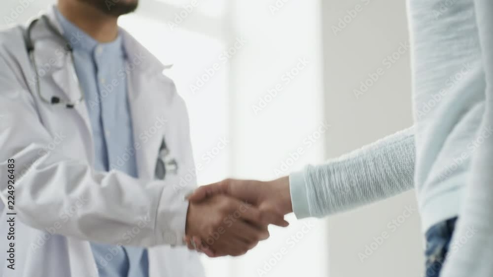 Close up shot of unrecognizable doctor in lab coat and female patient or colleague shaking hands, tracking left Close up shot of unrecognizable doctor in lab coat and female patient or colleague shaking hands, tracking left