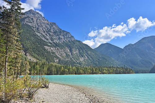 Beautiful turquoise Kinney Lake in Mount Robson Provincial Park. Forests and rocky mountains under blue sky. British Columbia, Canada.