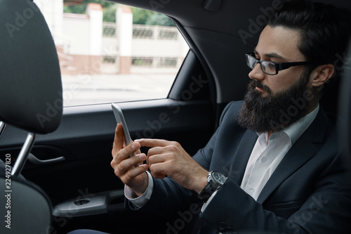 A businessman while traveling by car in the back seat using a sm © arthurhidden