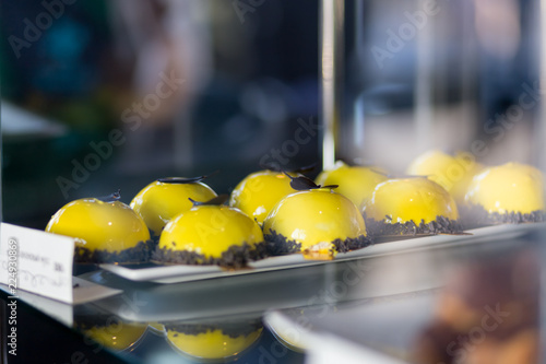 dessert with yellow icing decorated with chocolate on a shelf in a cafe