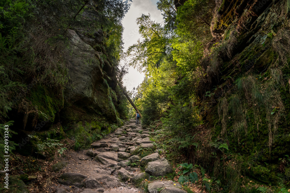 Wanderin mit Rucksack läuft einen steinigen Weg zwischen zwei Bergen hinauf Wanderin mit Rucksack läuft einen steinigen Weg zwischen zwei Bergen hinauf