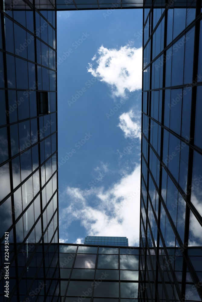 looking at the sky surrounded by windows of a modern office building