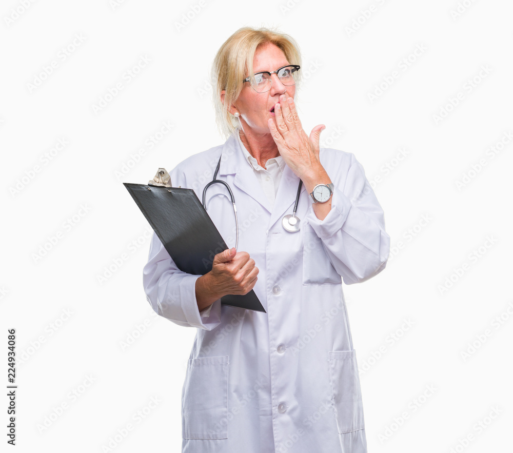 Middle age blonde doctor woman holding clipboard over isolated background cover mouth with hand shocked with shame for mistake, expression of fear, scared in silence, secret concept Middle age blonde doctor woman holding clipboard over isolated background cover mouth with hand shocked with shame for mistake, expression of fear, scared in silence, secret concept