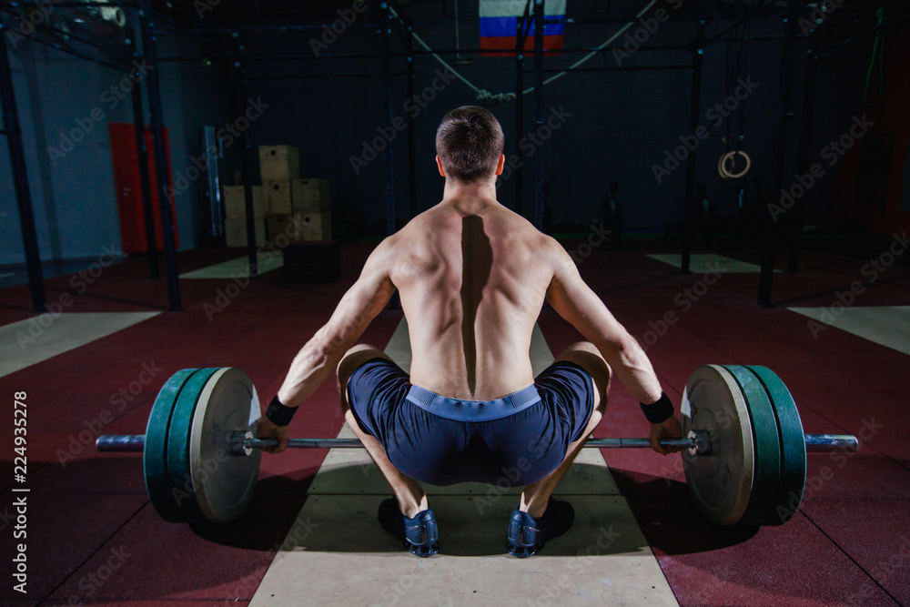 Muscular fitness man preparing to deadlift a barbell over his head in modern fitness center.Functional training.Snatch exercise. Muscular fitness man preparing to deadlift a barbell over his head in modern fitness center.Functional training.Snatch exercise.