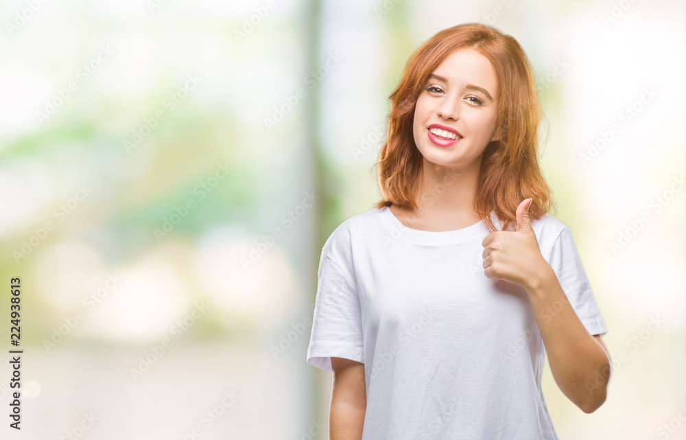 Young beautiful woman over isolated background doing happy thumbs up gesture with hand. Approving expression looking at the camera with showing success.
