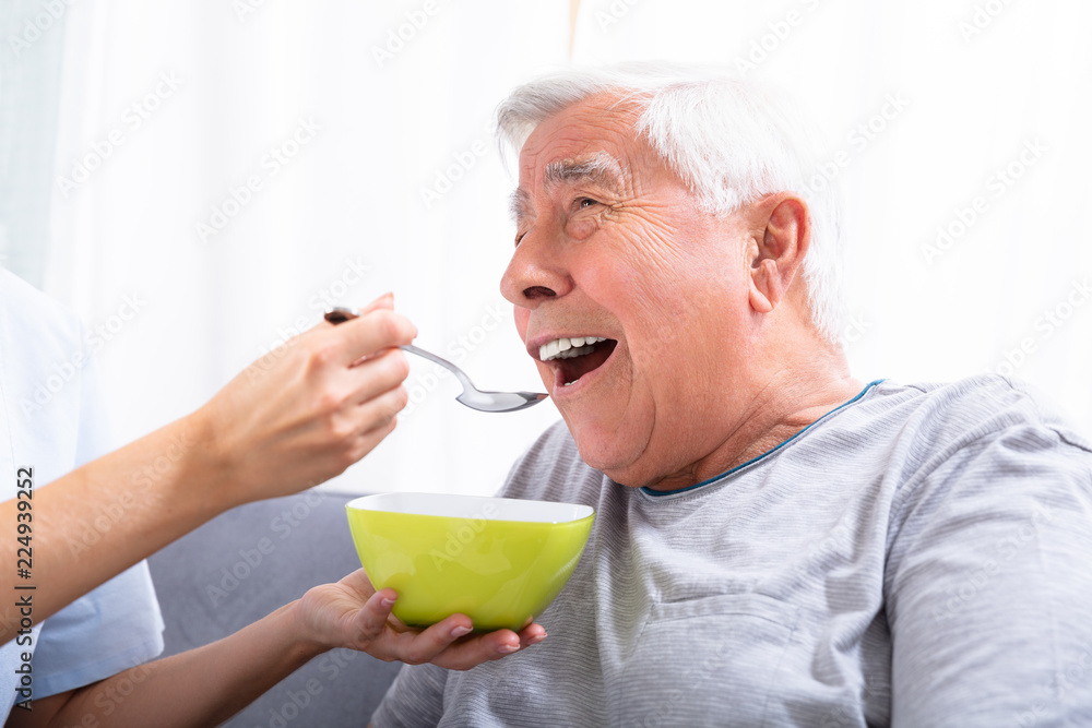 Caretaker Feeding Senior Man Caretaker Feeding Senior Man