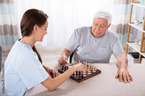 Female Caretaker Playing Chess With Senior Man
