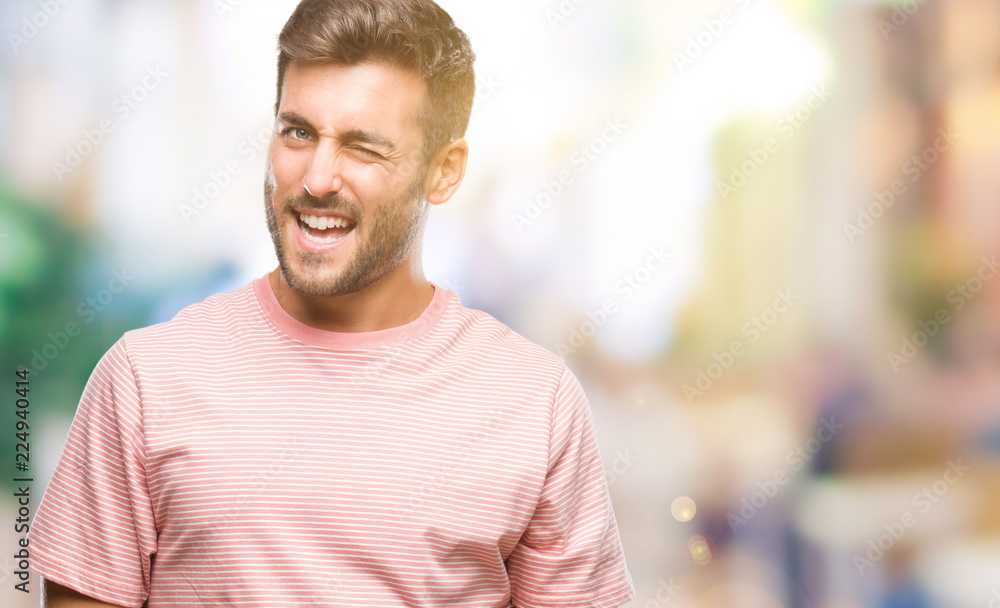 Young handsome man over isolated background winking looking at the camera with sexy expression, cheerful and happy face.