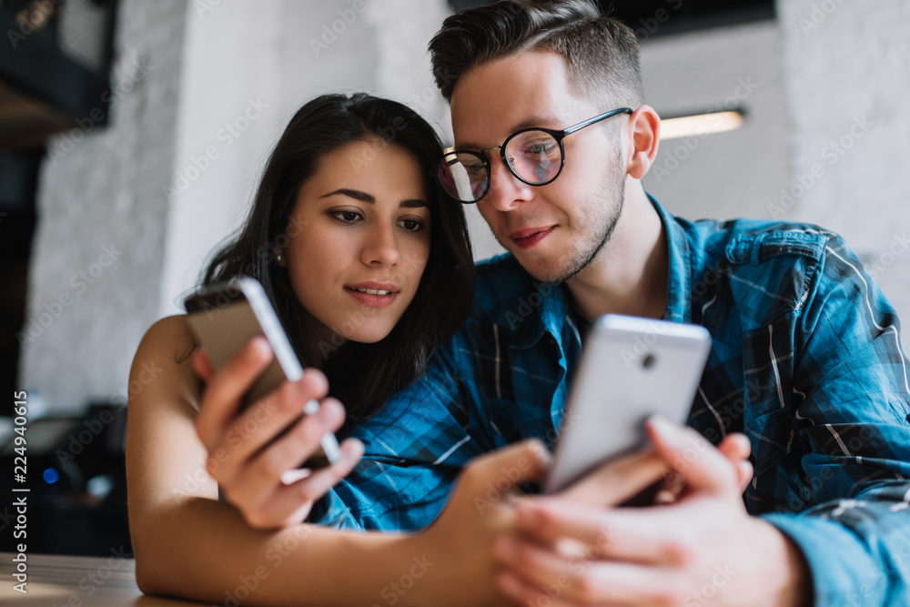 Stylish hipsters  using smartphones, searching online, learning language, online shopping. Friends ordering food