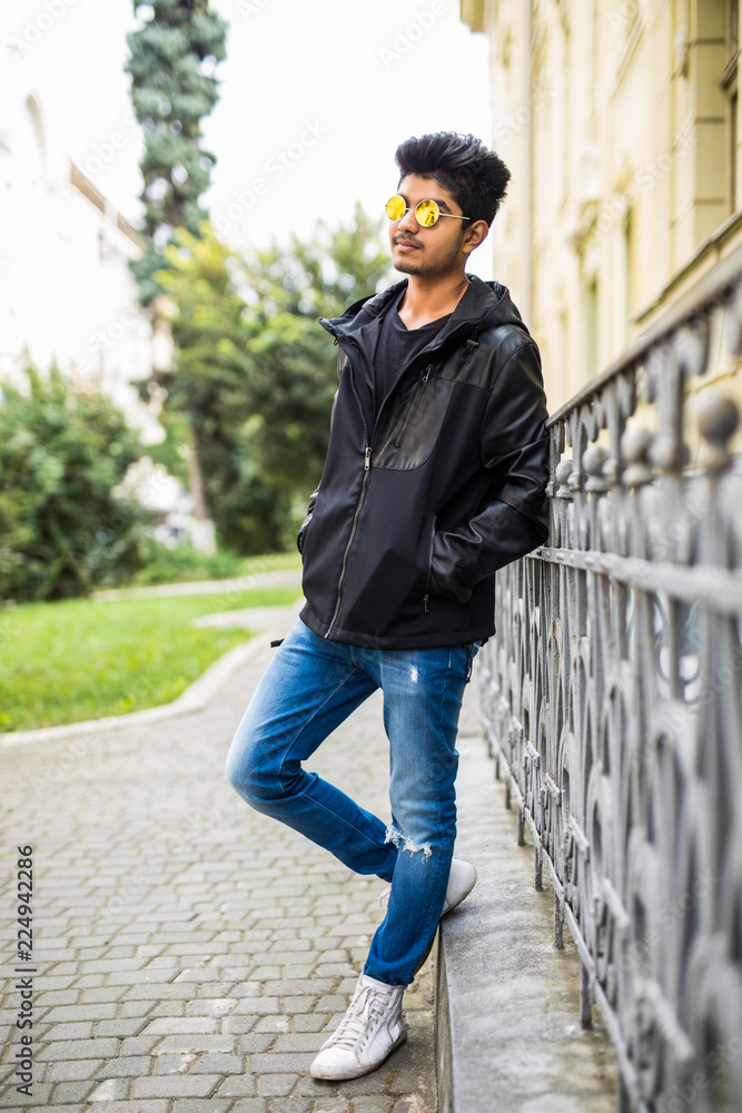 Young indian man at sunglasses walking outdoor sunset at streets of city. Young indian man at sunglasses walking outdoor sunset at streets of city.