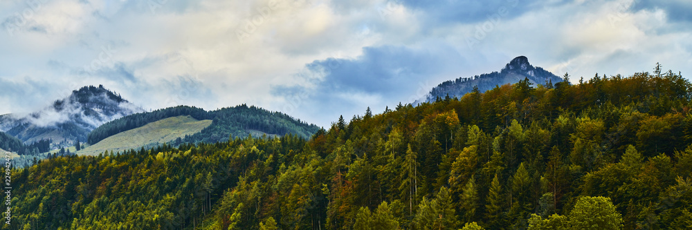 Beautiful landscape with colorful forests, Alpine mountains and dramatic sky near Wolfgangsee lake in Austria.