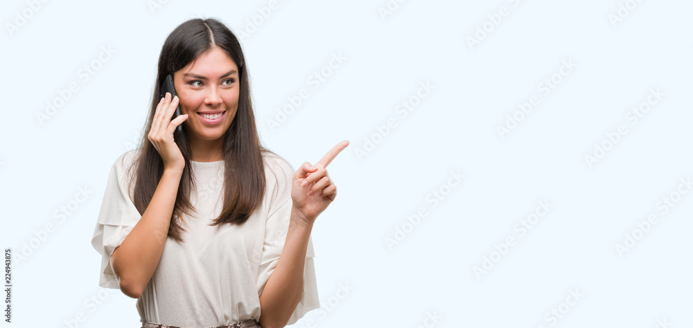 Young beautiful hispanic using smartphone very happy pointing with hand and finger to the side Young beautiful hispanic using smartphone very happy pointing with hand and finger to the side