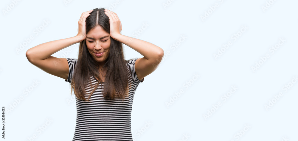 Young beautiful hispanic woman suffering from headache desperate and stressed because pain and migraine. Hands on head. Young beautiful hispanic woman suffering from headache desperate and stressed because pain and migraine. Hands on head.