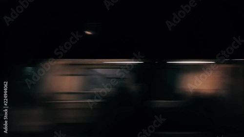 Passenger train approaching to the station at night. Outside view from the window.