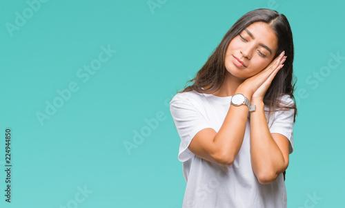 Young beautiful arab woman over isolated background sleeping tired dreaming and posing with hands together while smiling with closed eyes.