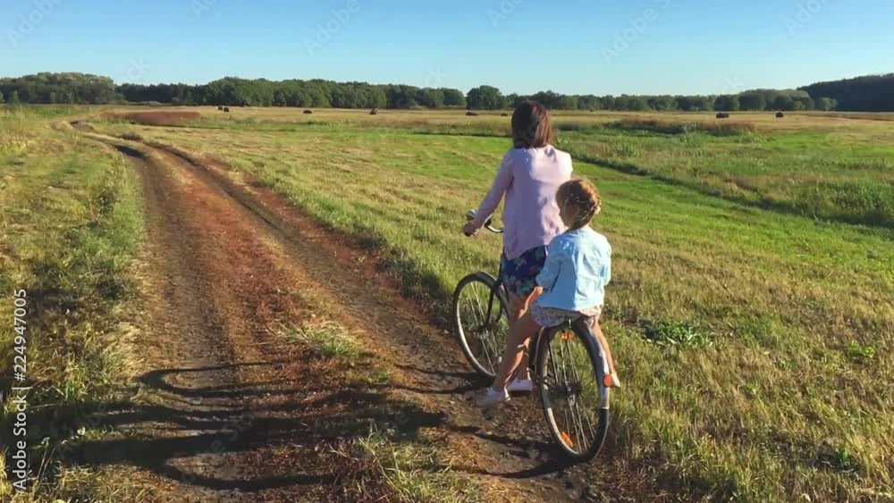 Mother with daughter on bicycles in a meadow. Family on bicycles in nature. The concept of the family. Mother with daughter on bicycles in a meadow. Family on bicycles in nature. The concept of the family.