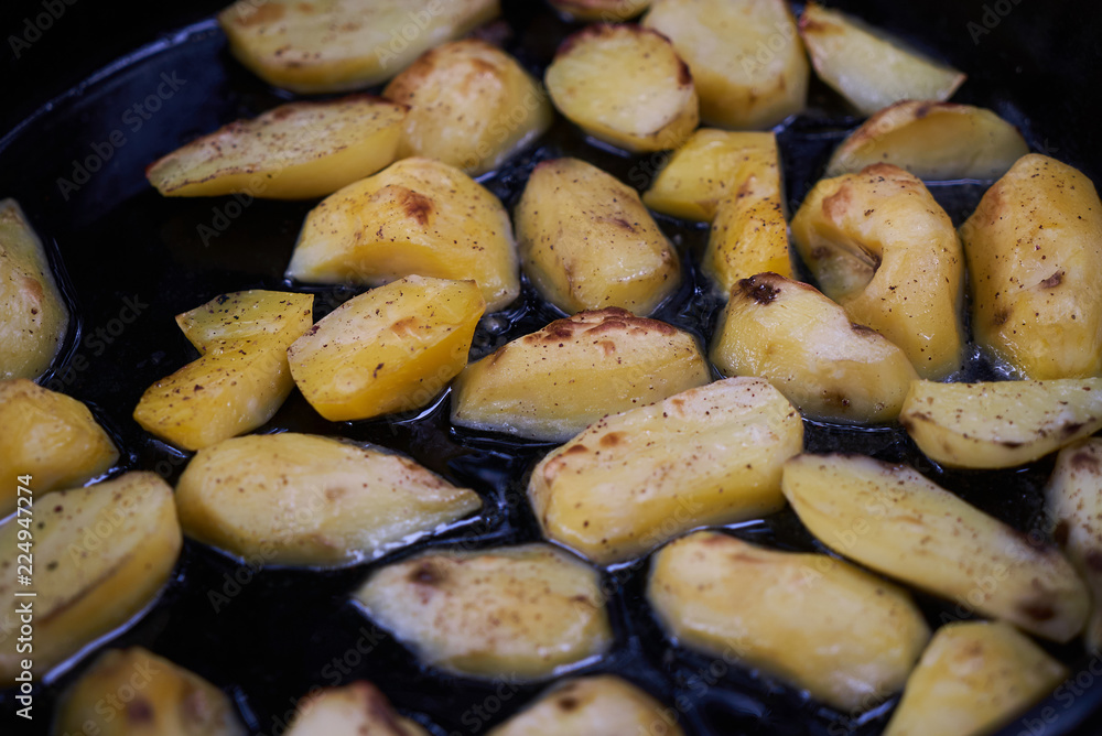 Baked fried potatoes in iron frying pan, close-up Baked fried potatoes in iron frying pan, close-up