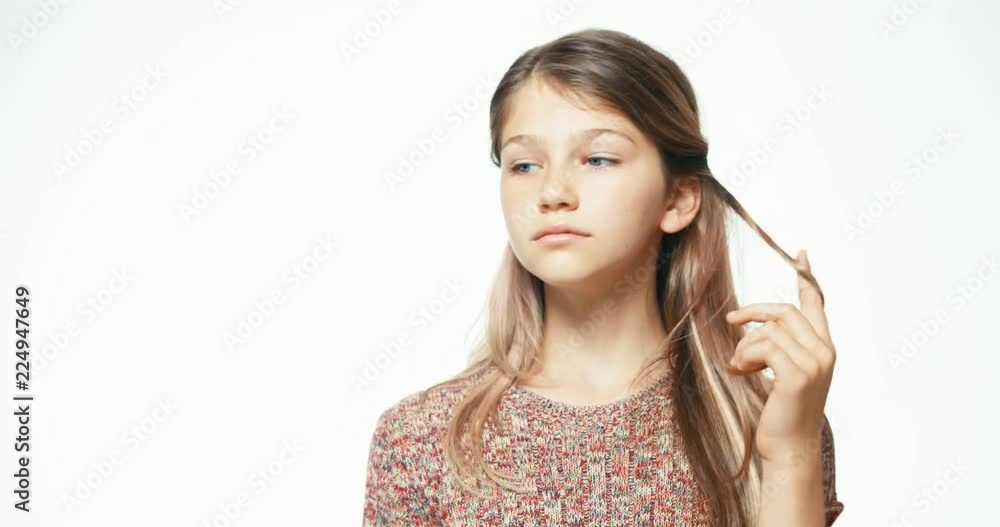 Teenage girl posing at camera, touching her hair and smiling on the white background. Close up portrait Teenage girl posing at camera, touching her hair and smiling on the white background. Close up portrait