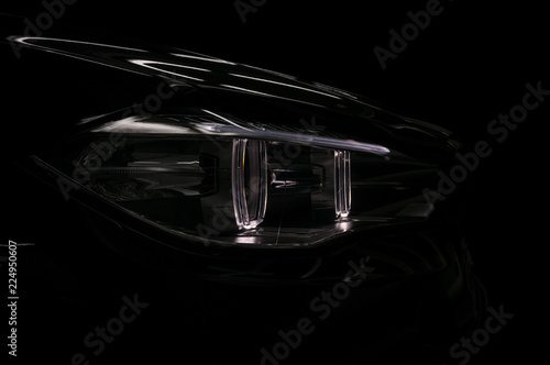 Car headlight on black background. Exterior detail. © alexdemeshko