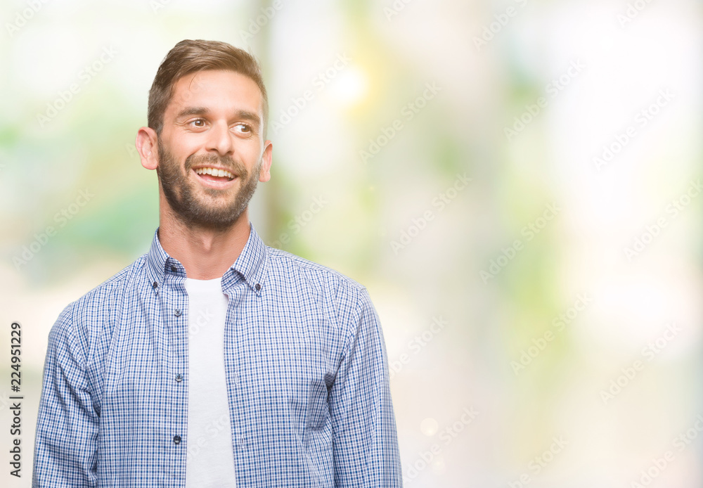 Young handsome man wearing white t-shirt over isolated background looking away to side with smile on face, natural expression. Laughing confident. Young handsome man wearing white t-shirt over isolated background looking away to side with smile on face, natural expression. Laughing confident.