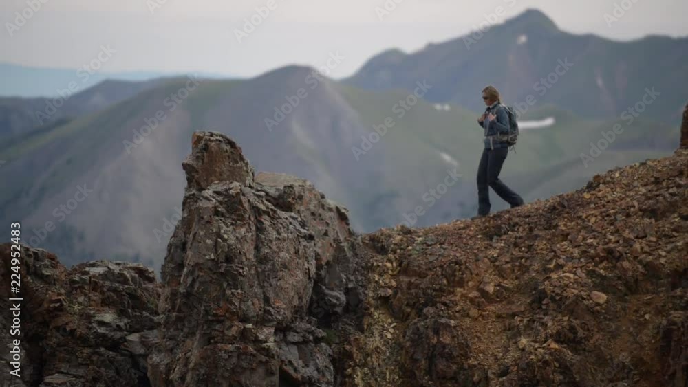 Girl Hiker walks along steep ridge to conquer the mountain Girl Hiker walks along steep ridge to conquer the mountain