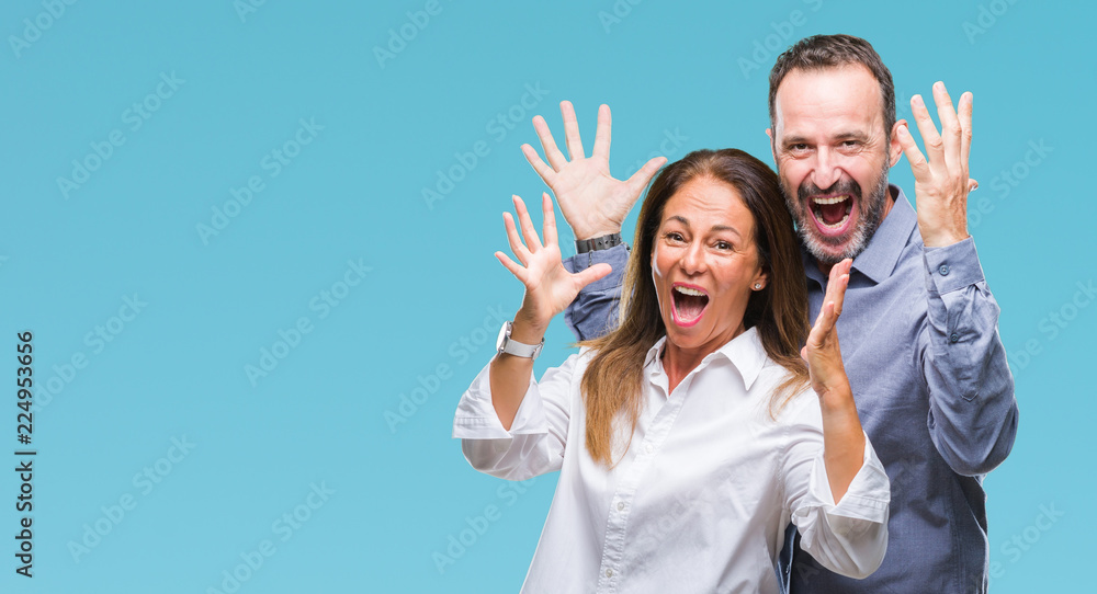 Middle age hispanic business couple over isolated background celebrating crazy and amazed for success with arms raised and open eyes screaming excited. Winner concept Middle age hispanic business couple over isolated background celebrating crazy and amazed for success with arms raised and open eyes screaming excited. Winner concept