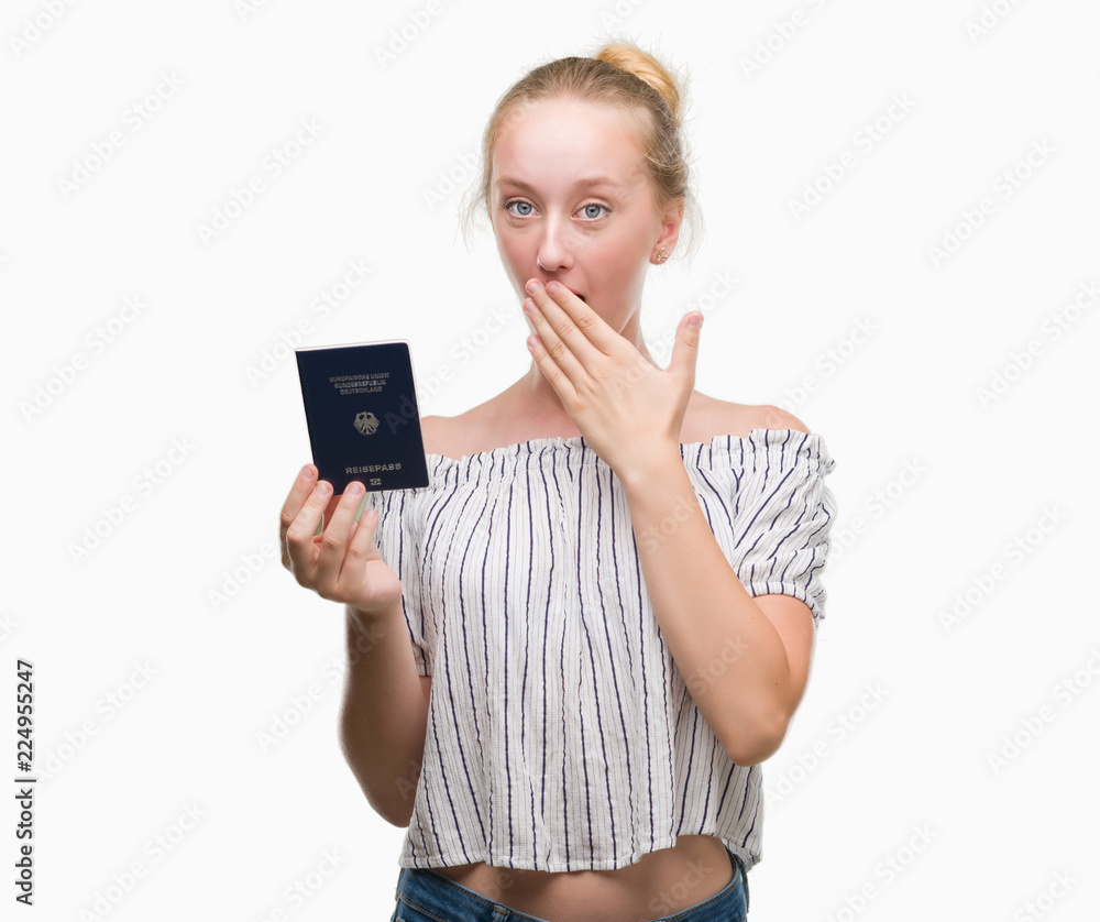 Blonde teenager woman holding passport of Germany cover mouth with hand shocked with shame for mistake, expression of fear, scared in silence, secret concept Blonde teenager woman holding passport of Germany cover mouth with hand shocked with shame for mistake, expression of fear, scared in silence, secret concept